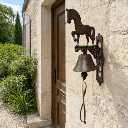 Grande cloche de porte cheval en fonte sur façade en pierre
