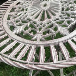 Salon de jardin bistrot patiné marron en fer et fonte vue du motif en fonte de la table 