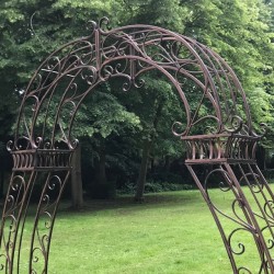 Détail des volutes supérieures de l’arche à rosiers en métal marron patiné