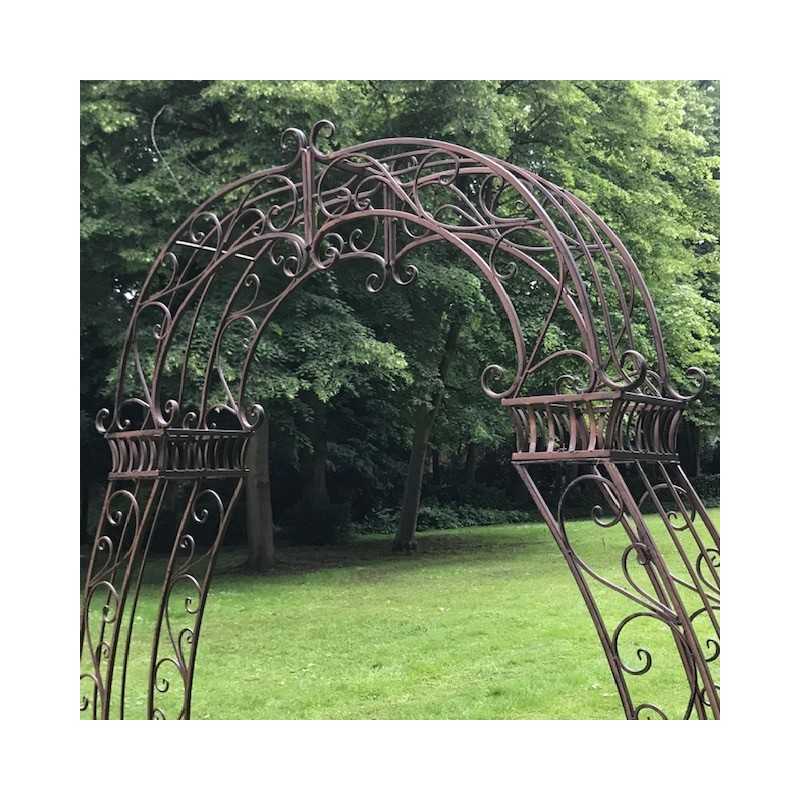 Détail des volutes supérieures de l’arche à rosiers en métal marron patiné