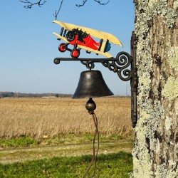Vue rapprochée de la cloche en fonte et de son motif d’avion vintage
