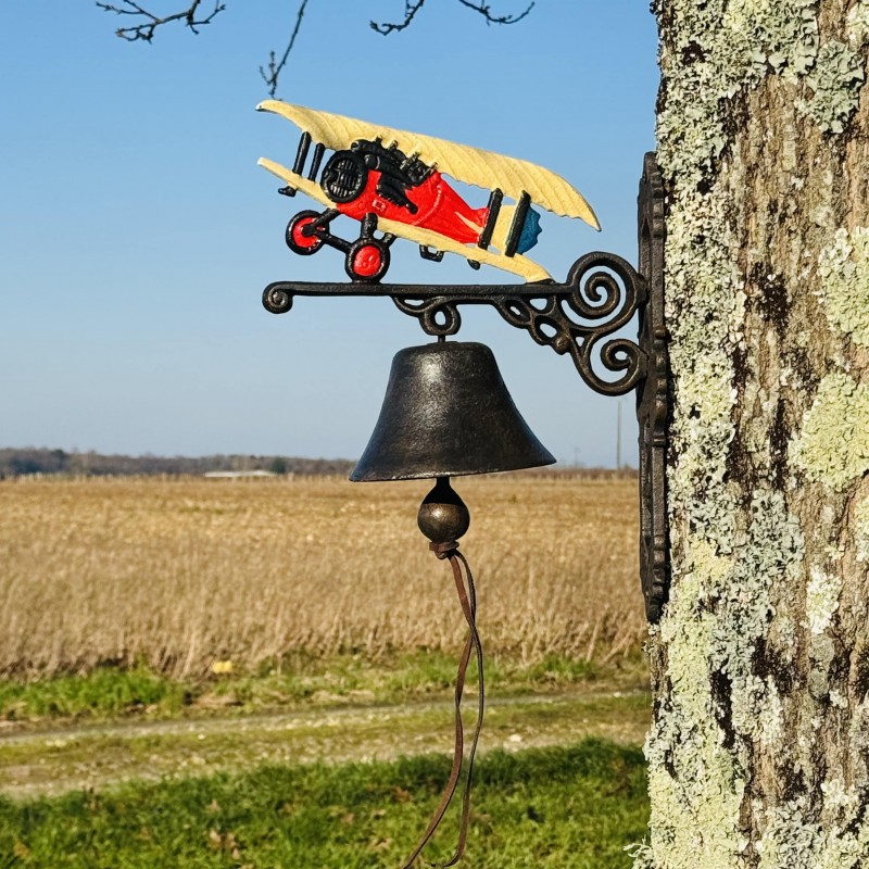 Vue rapprochée de la cloche en fonte et de son motif d’avion vintage