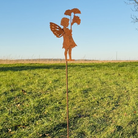 Pique décoratif en métal rouillé avec un personnage féerique installé dans un jardin.