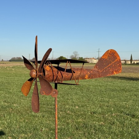 Avion éolienne en métal rouillé installé dans un jardin