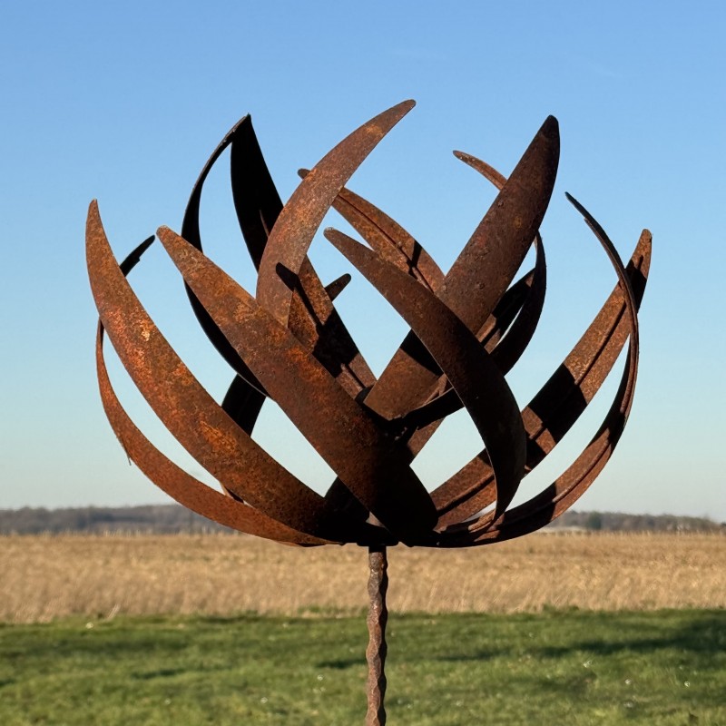 Vue complète de l’éolienne sculpturale en métal rouillé sous un ciel dégagé
