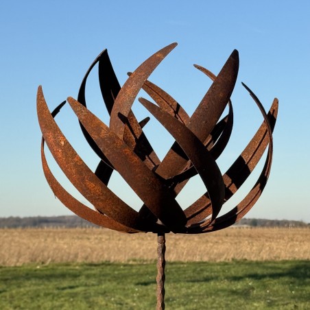 Vue complète de l’éolienne sculpturale en métal rouillé sous un ciel dégagé