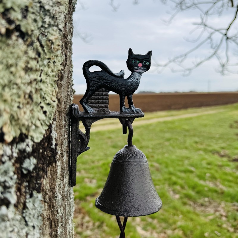 Cloche murale en fonte avec chat noir – en situation dans un jardin