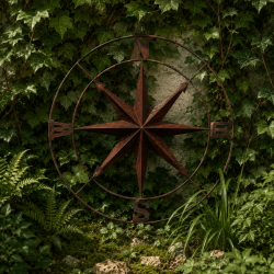 Grande rose des vents murale en métal rouillé dans un jardin