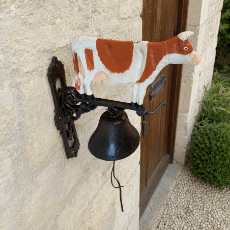 Sonnette murale vache installée près d’une porte d’entrée